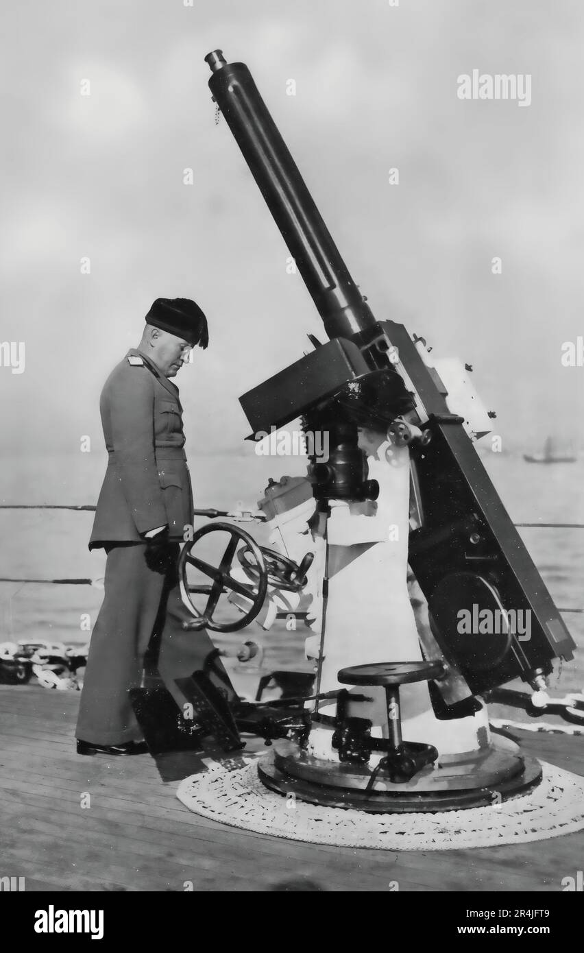 El dictador italiano Benito Mussolini (il duce) inspeccionando un arma de artillería pesada. Foto de stock