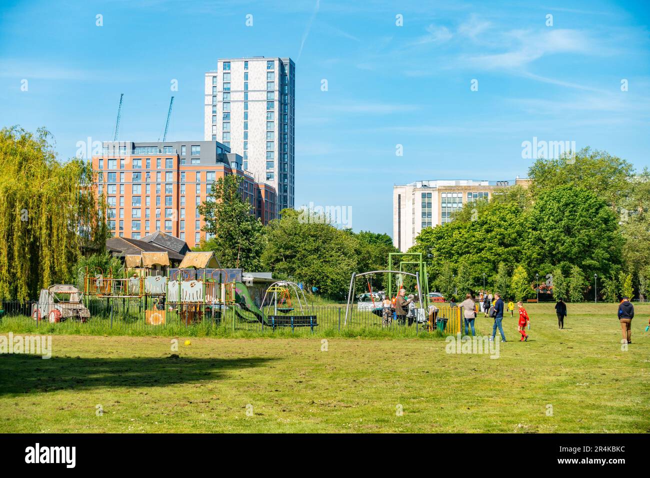 Una vista de Kings Meadow Park en Reading, Berkshire, Reino Unido con modernos bloques de torres en la distancia y un patio de juegos para niños en primer plano. Foto de stock