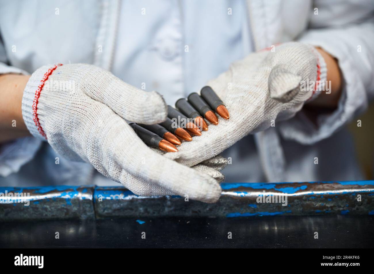 Mujer en guantes clasifica cartuchos terminados en el lugar de trabajo de  la planta Fotografía de stock - Alamy
