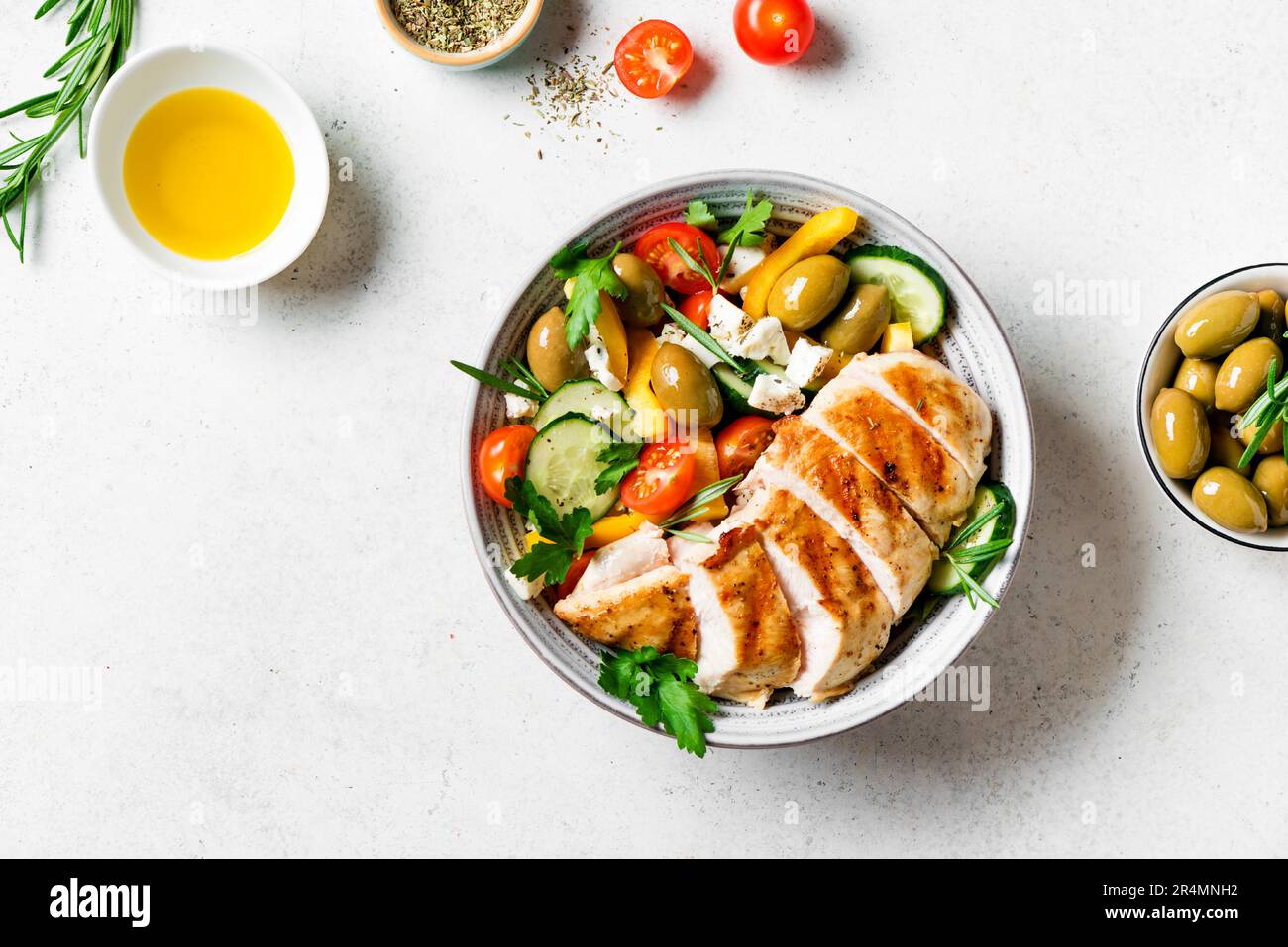 Filete de pollo a la parrilla y ensalada griega de verduras frescas en blanco, vista superior, espacio de copia. Saludable keto, comida cetogénica - carne de pechuga de pollo asada, oli Foto de stock