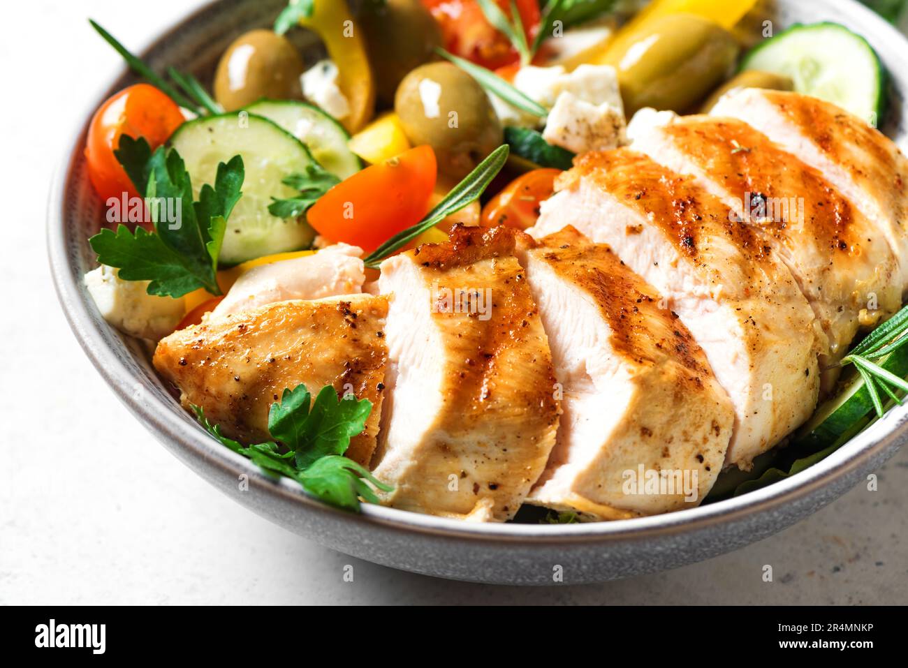 Filete de pollo a la parrilla y ensalada griega de verduras frescas de cerca. Saludable keto, comida cetogénica: Carne de pechuga de pollo asada, aceitunas, queso feta, verduras Foto de stock