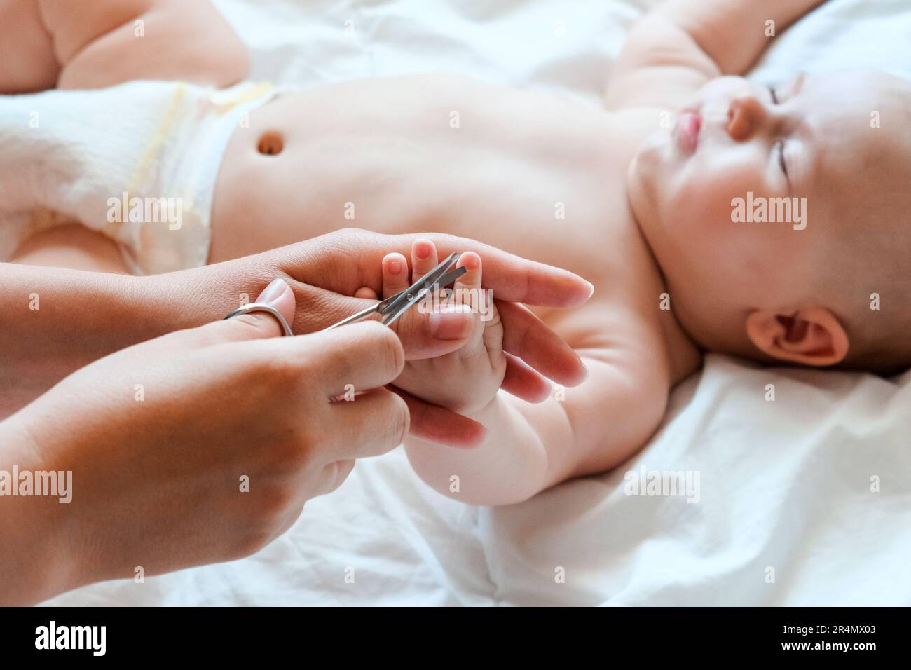 Bebé recibiendo uñas cortadas mientras duerme por su madre con