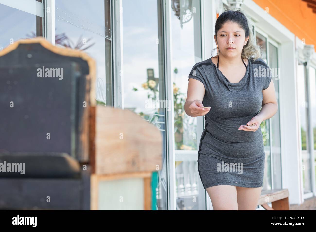 mujer latina joven jugando el juego llamado rana, preparándose en posición de tiro para disparar el aro. Foto de stock