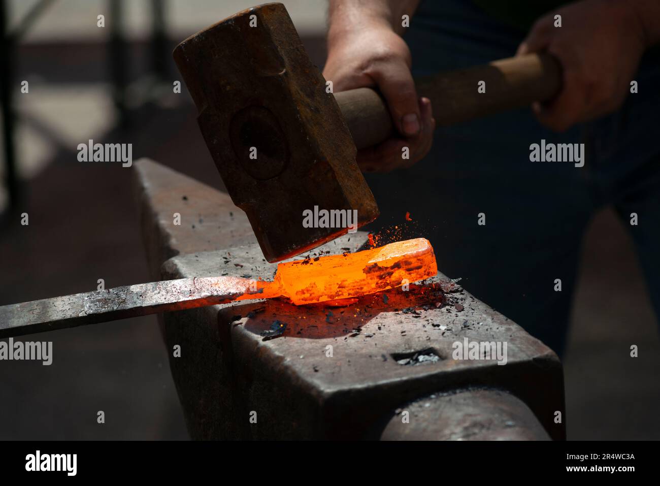 Herrero forja una pieza de hierro al rojo vivo Fotografía de stock - Alamy