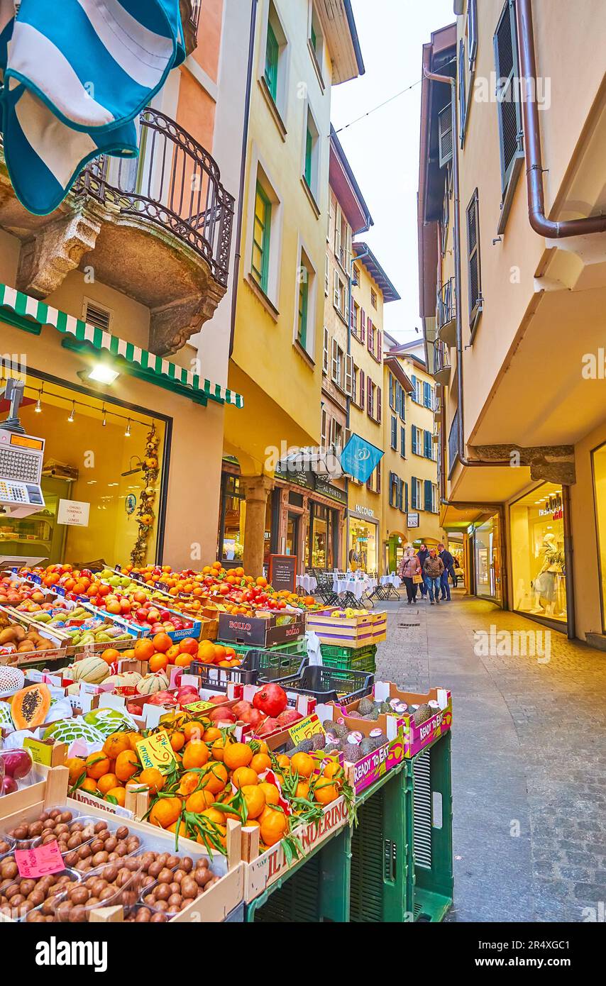 El pequeño puesto de frutas con naranjas frescas, manzanas, kiwies, granadas y otras frutas frente a la estrecha calle Via Pessina, Lugano, Suiza Foto de stock