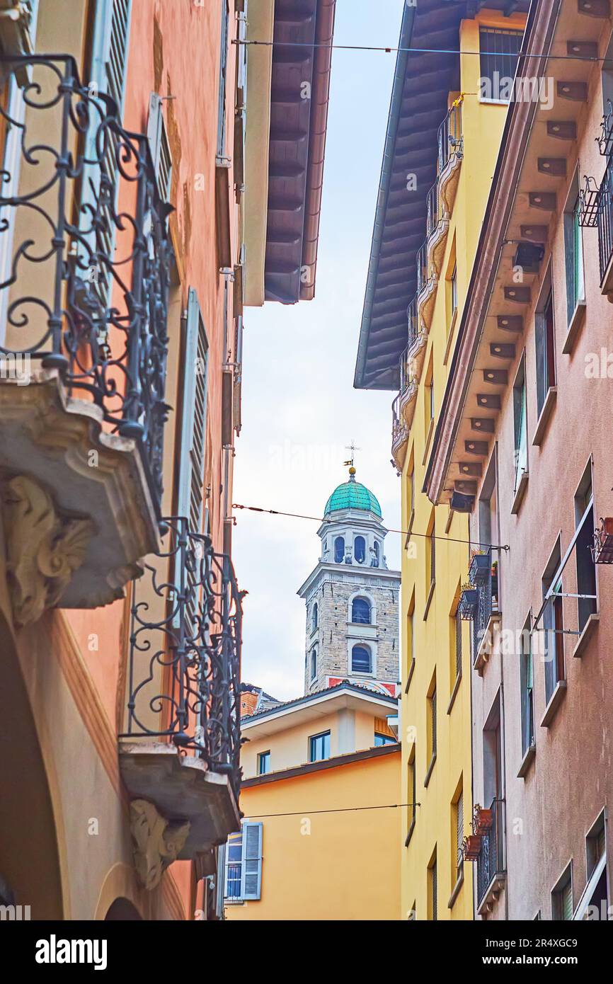 El antiguo campanario de piedra de la catedral de San Lorenzo, visto a través del hueco entre las casas en Via Pessina, Lugano, Suiza Foto de stock