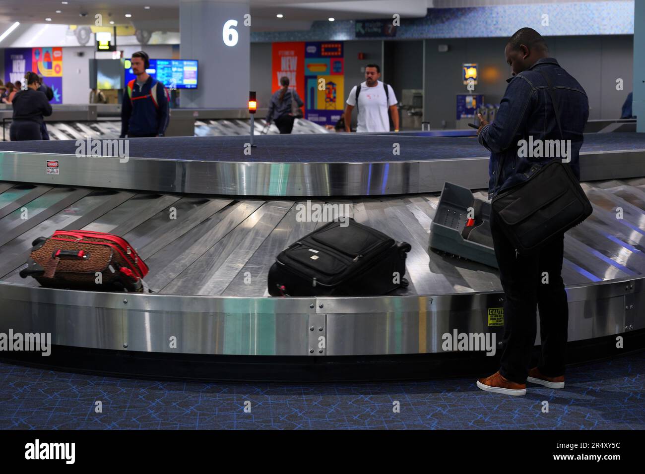 Personas que esperan recoger el equipaje de un carrusel de equipaje en la zona de recogida de equipajes de la Terminal B del aeropuerto de LaGuardia, en la ciudad de Nueva York. Foto de stock