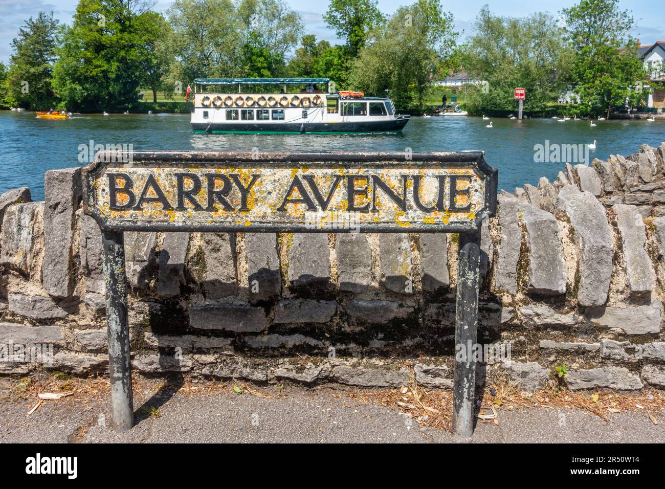 Una señal de la calle de Barry Avenue en Windsor, Reino Unido con un barco de crucero en el río Támesis detrás. Foto de stock