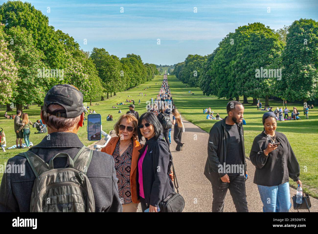 Los amigos se detienen y posan para una fotografía en el Long Walk en Windsor, ocupado con los visitantes en un día soleado de mayo Foto de stock