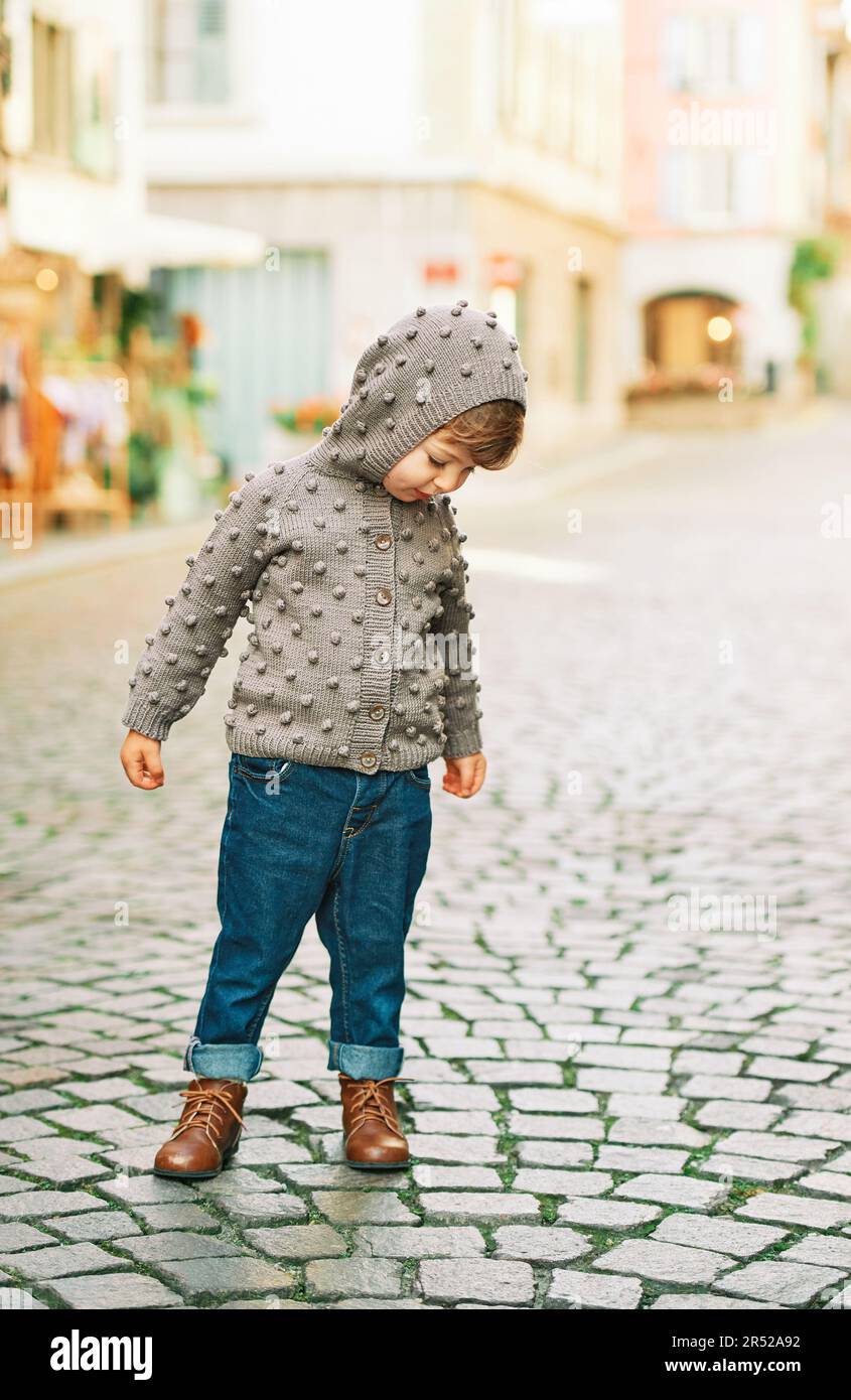 Retrato al aire libre de niña linda que chaqueta de punto marrón y jeans azules oscuros, moda niños pequeños Fotografía de stock - Alamy