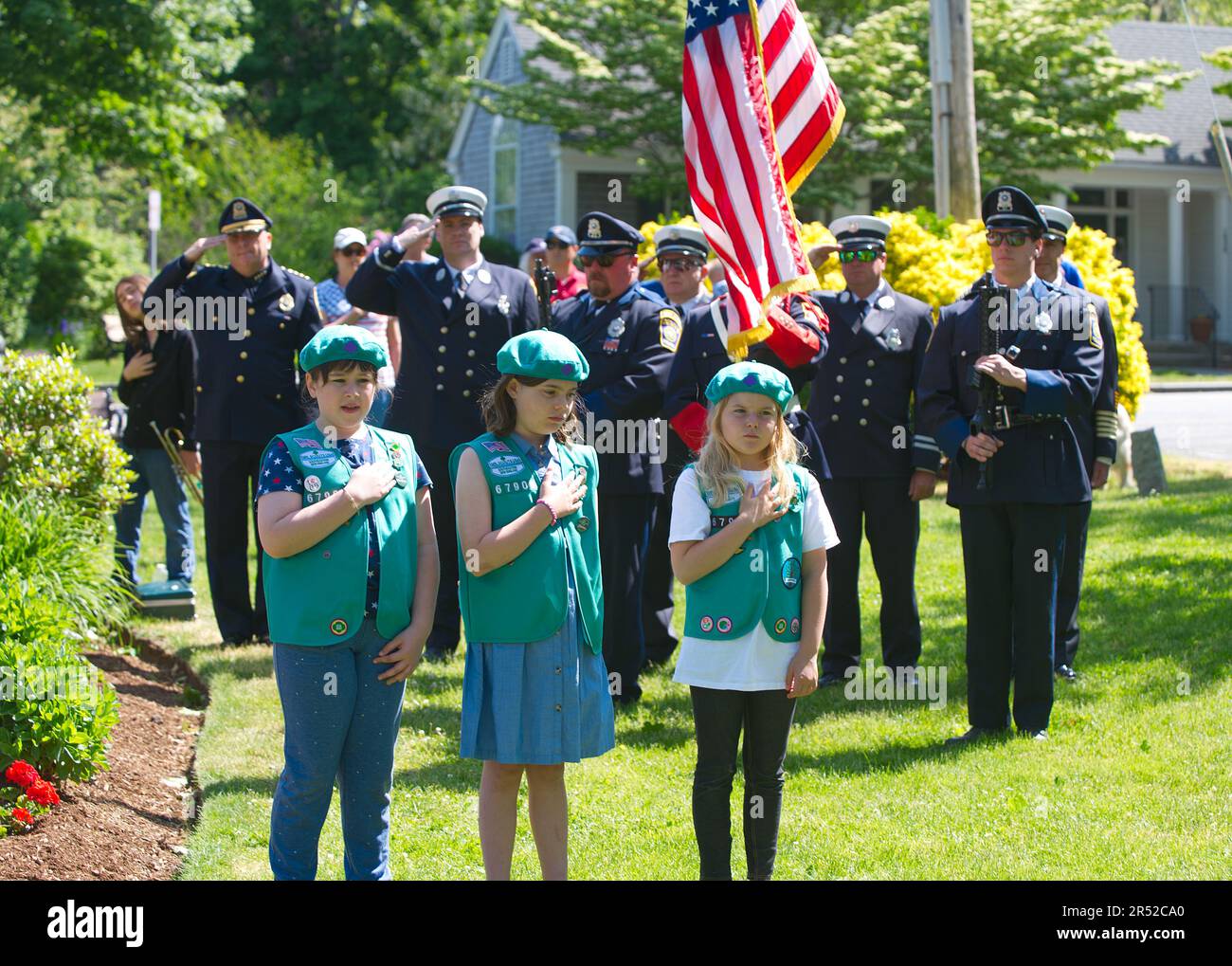 Evento del Día de los Caídos. Dennis, Massachusetts, (Cape Cod), Estados Unidos. Niñas Scouts y Cuerpo de Bomberos Guardia de Color durante el Himno Nacional Foto de stock