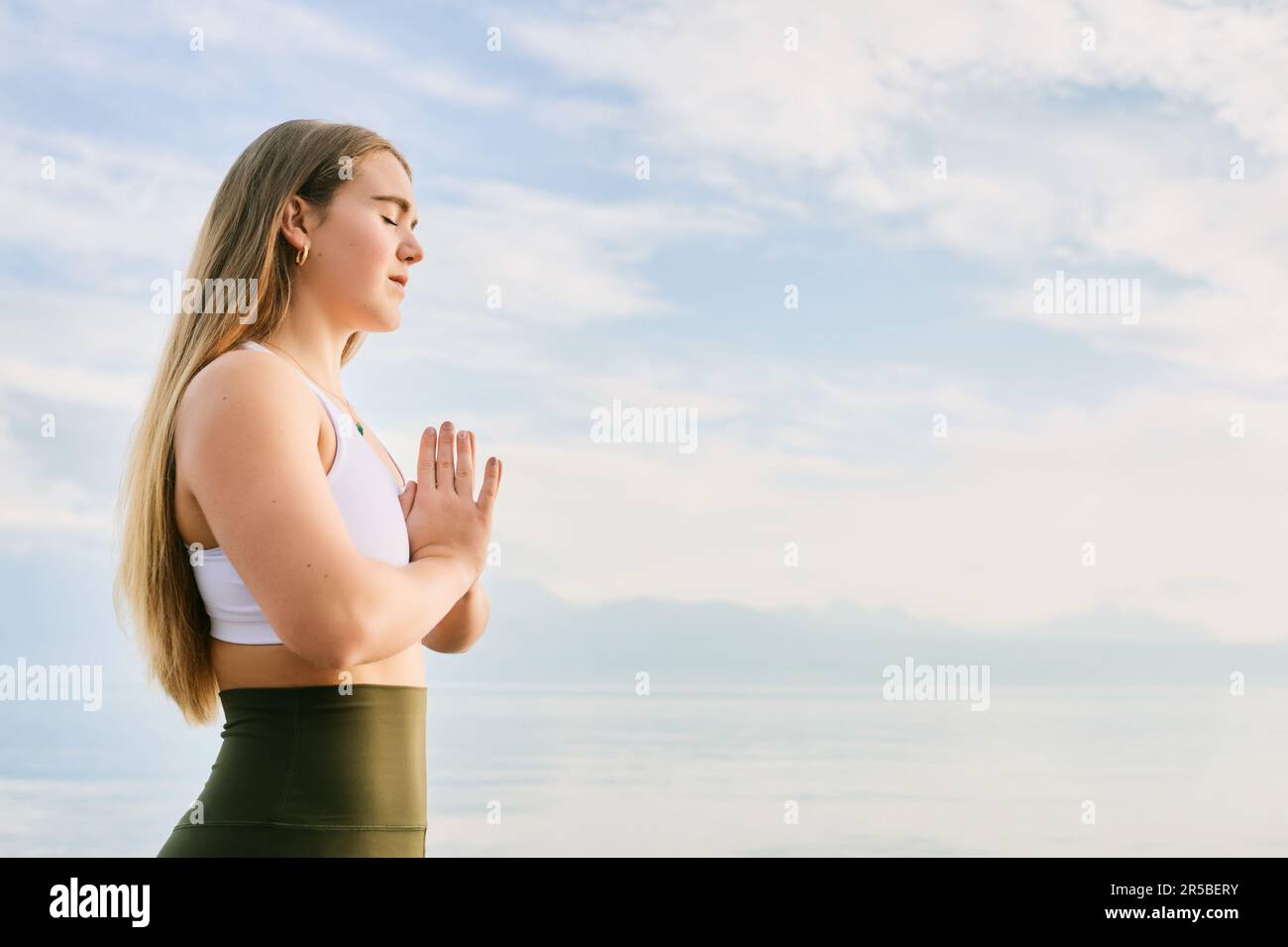 Hermosa mujer espiritual meditando junto al lago, gesto de namaste Foto de stock