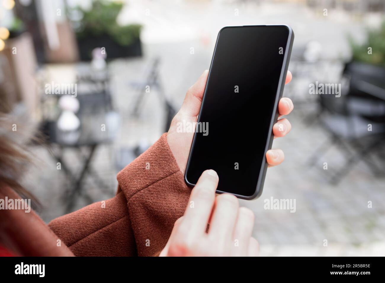 Imagen recortada de la mano de la mujer que sostiene el teléfono inteligente con la pantalla en blanco del espacio de la copia para su mensaje de texto o contenido promocional Foto de stock