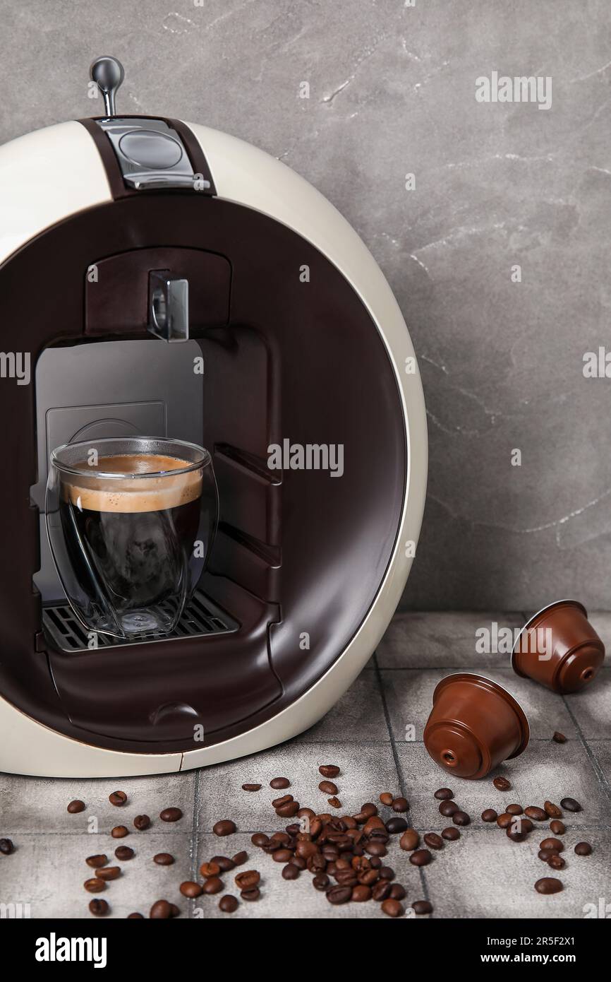 Moderna cafetera de cápsulas con taza de espresso, vainas y granos en mesa  grunge gris Fotografía de stock - Alamy