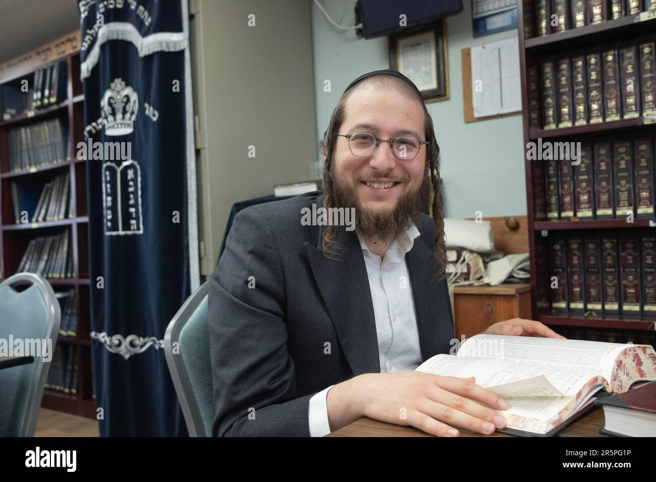 Un hombre judío ortodoxo hace una pausa en sus estudios de Talmud para sonreír por esta foto. En Monsey, condado de Rockland, Nueva York. Foto de stock