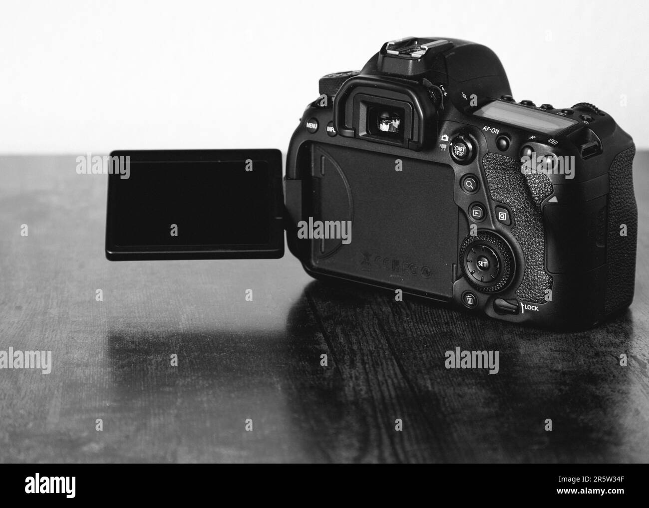 Una toma en escala de grises de una cámara DSLR profesional de Canon sobre la mesa Foto de stock