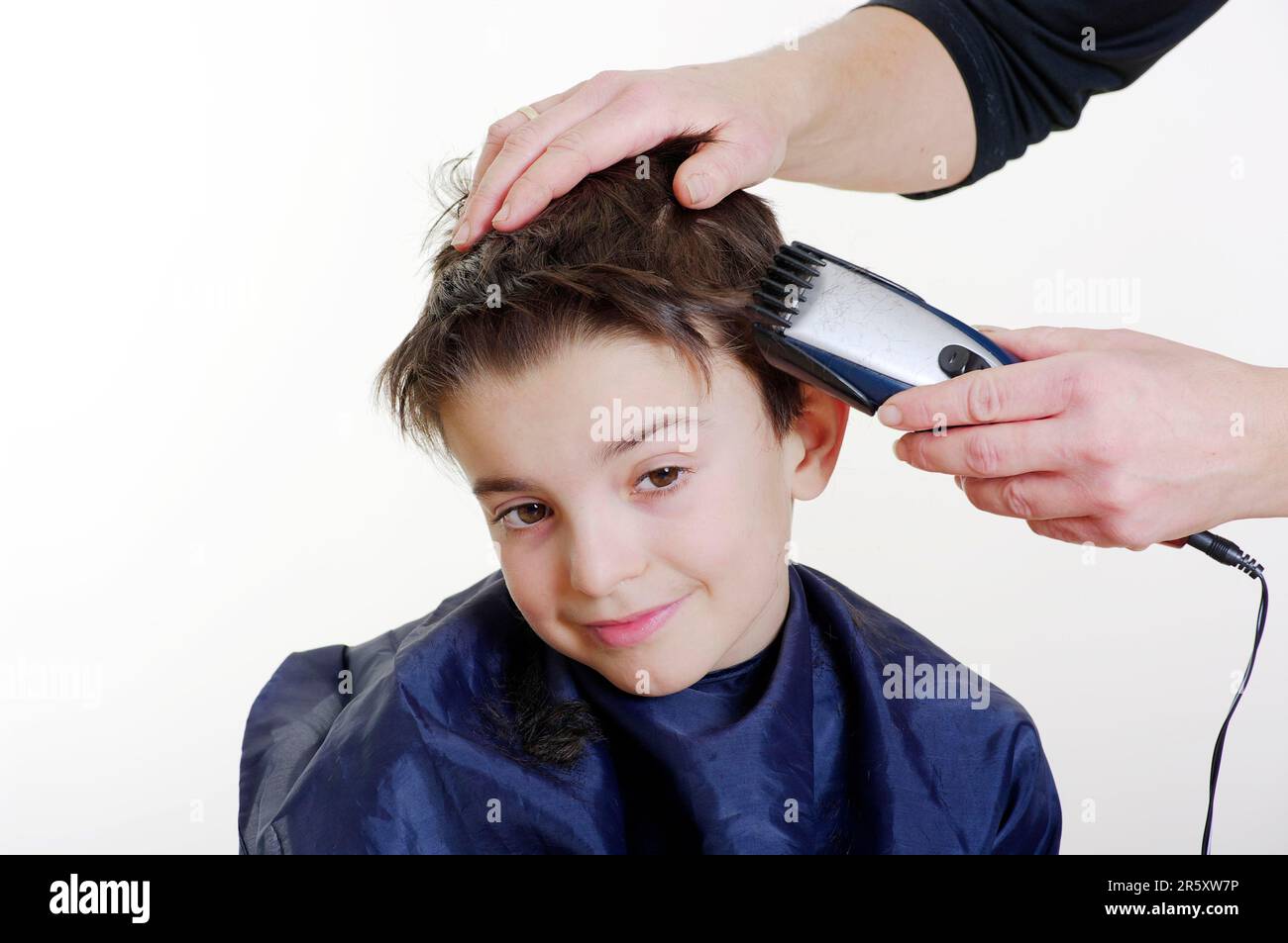 Chico se corta el pelo con un cortapelos, cortar el pelo Foto de stock
