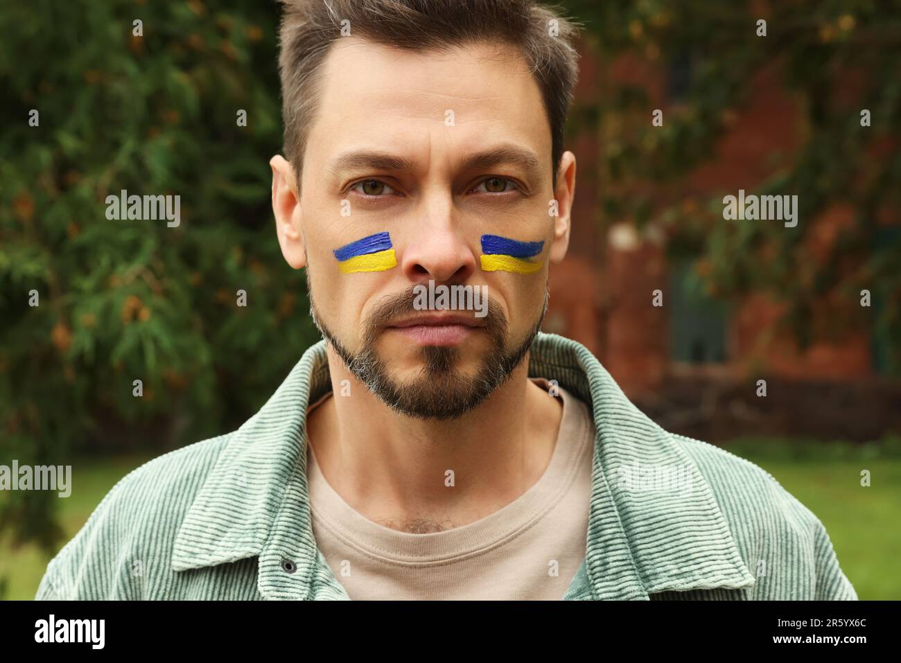 Hombre con dibujos de bandera ucraniana en la cara al aire libre Foto de stock
