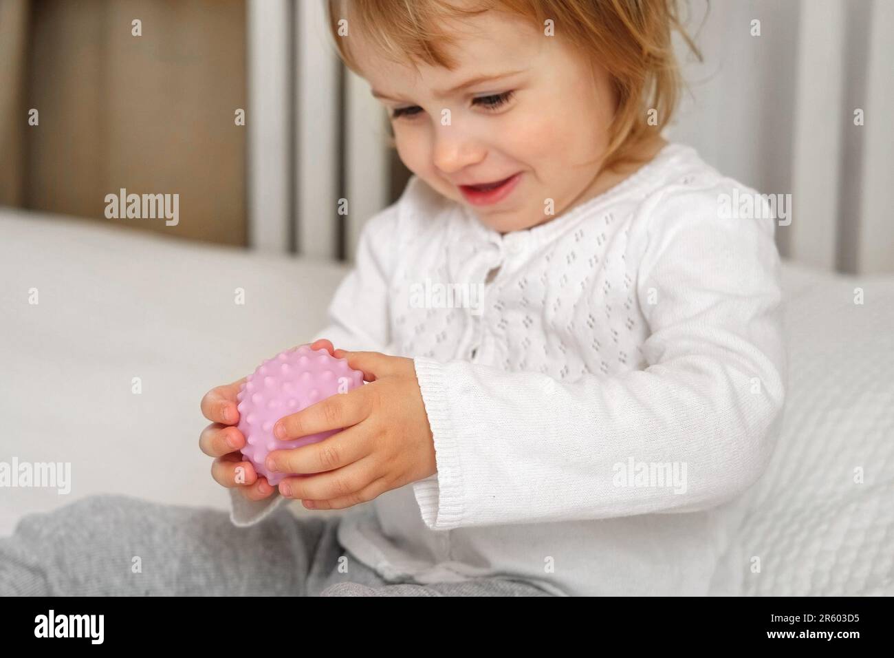 Lindo bebé niña jugando bolas táctiles knobby. La mano del niño pequeño juega la bola del masaje sensorial. Mejorar el proceso cognitivo y físico. Desarrollo del cerebro. Foto de stock