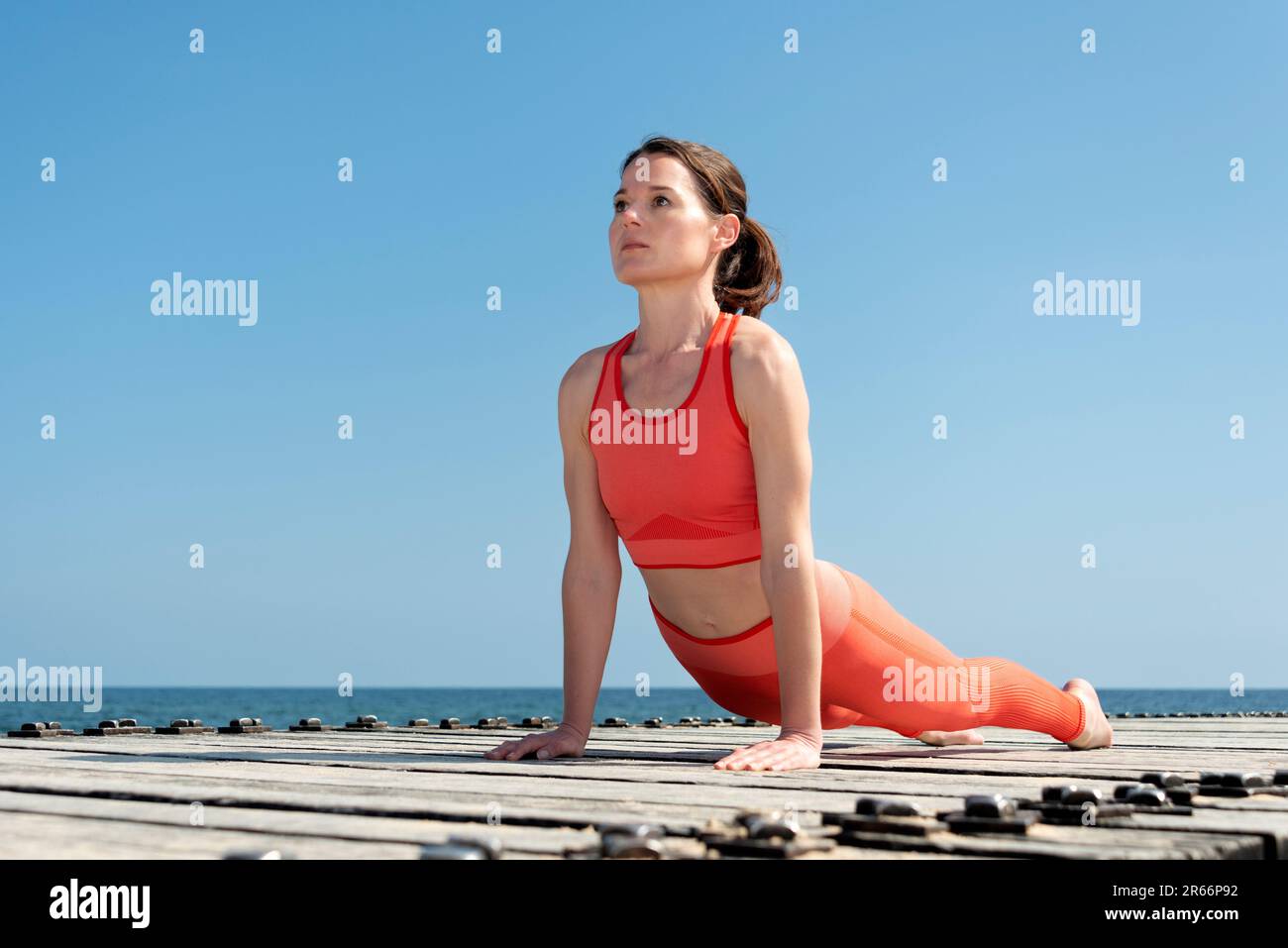 Mujer haciendo ejercicio de tablón afuera por el mar. Foto de stock