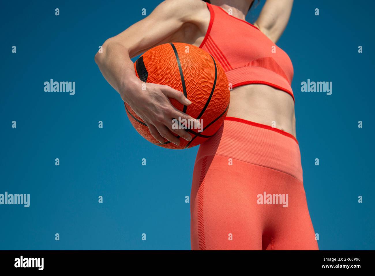 Cerca de una mujer deportiva sosteniendo un baloncesto debajo de su brazo Foto de stock