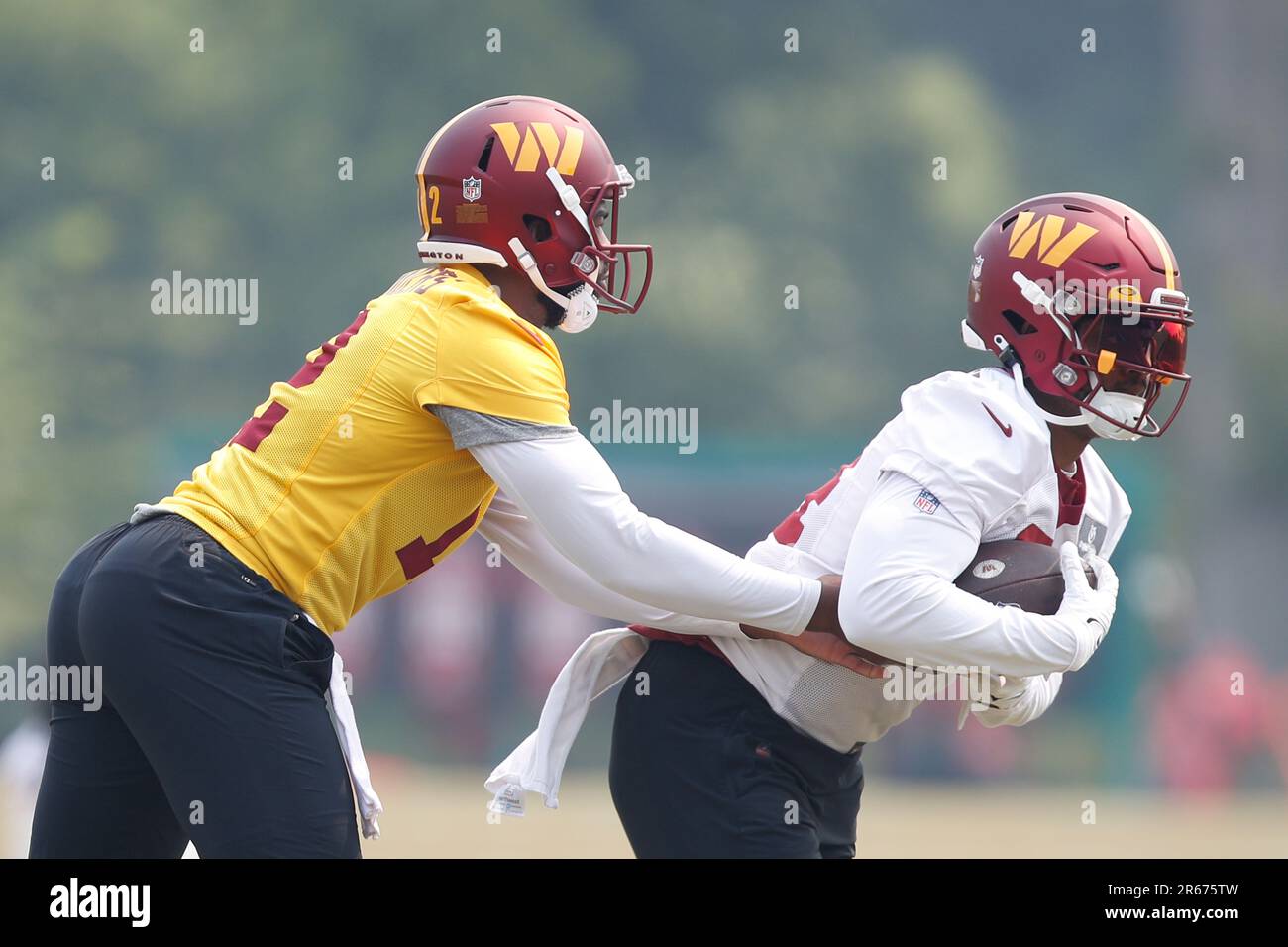 Washington Commanders quarterbacks Jacoby Brissett, left, hands the