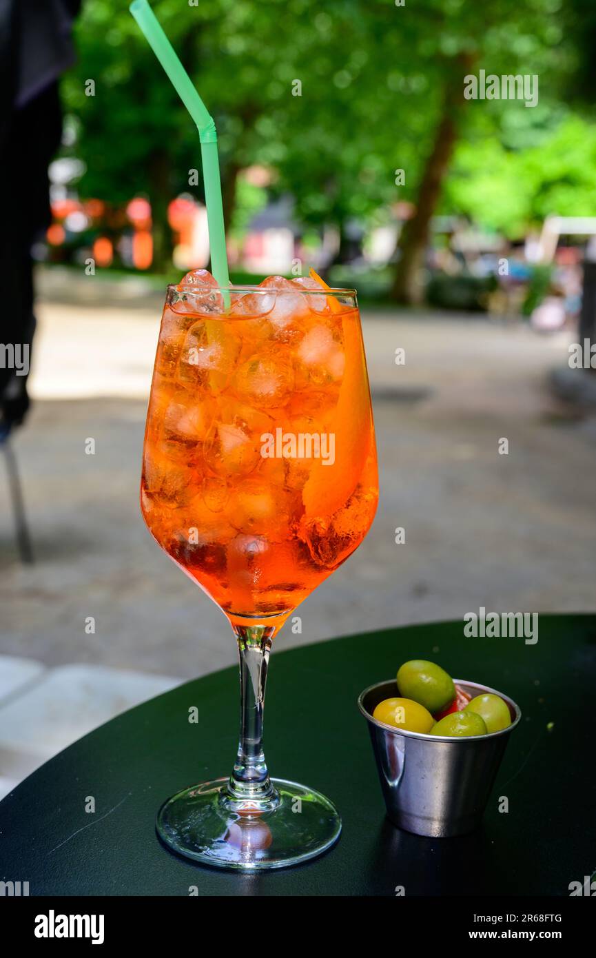 El camarero preparó el cóctel de verano Aperol Sprits con Aperol, prosecco,  cubitos de hielo, agua tónica y naranja en copa de vino, listo para beber  en terr soleado Fotografía de stock -