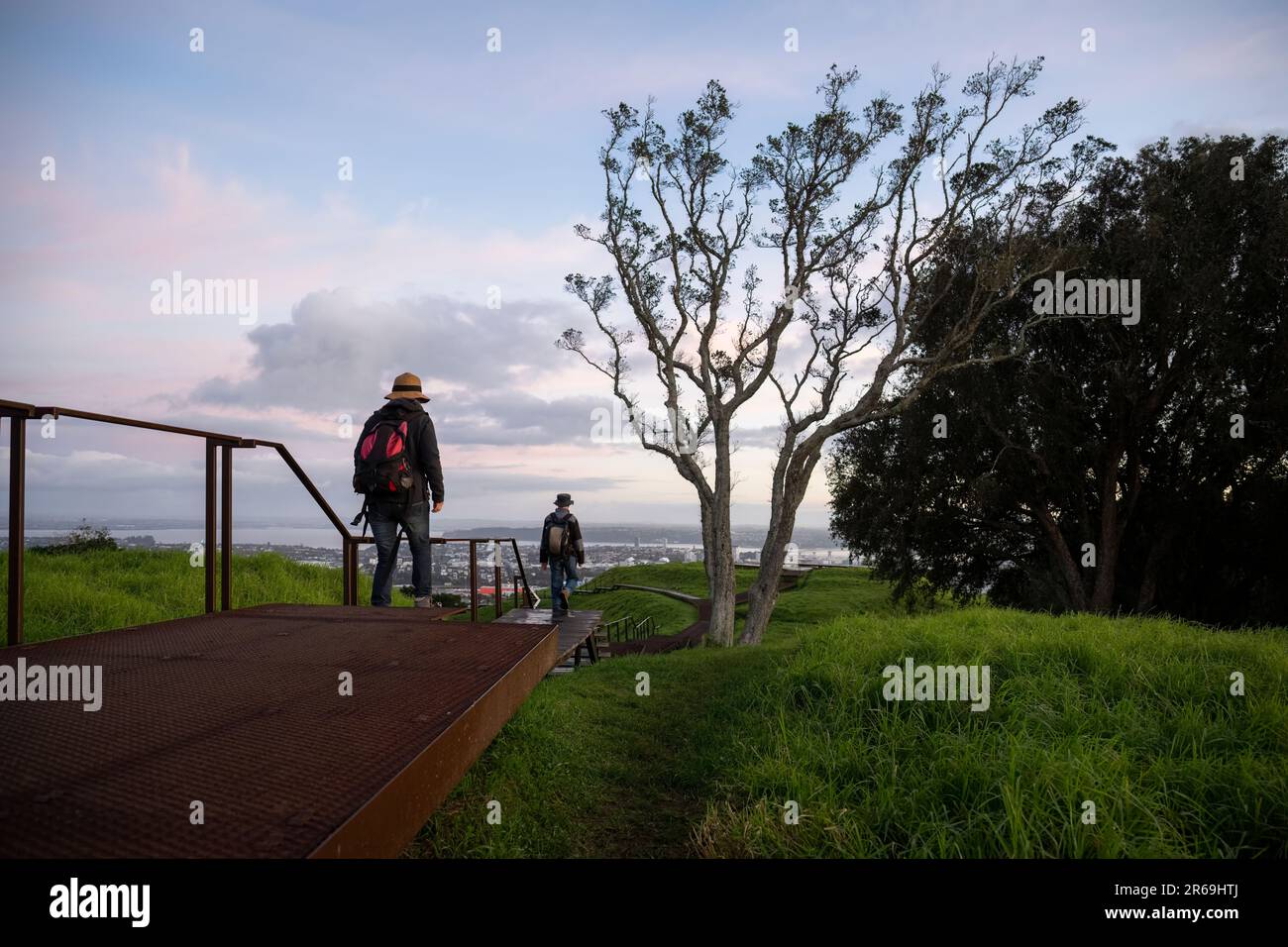 Gente caminando en el paseo marítimo elevado alrededor del cráter en la cumbre del Monte Eden al amanecer. Auckland. Foto de stock