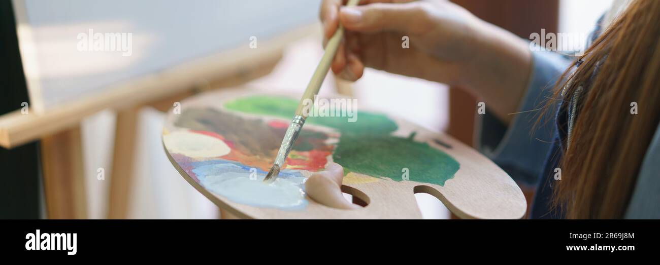 Pintor femenino joven mezcla el color en la paleta para pintar obras de  arte en lienzo con disfrutar en estudio casero Fotografía de stock - Alamy