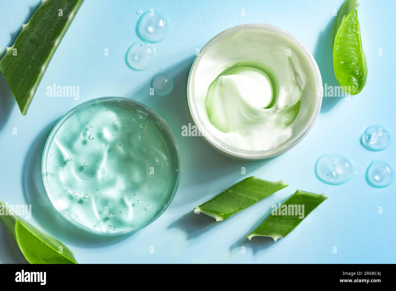 Hojas de planta de aloe vera y gel cosmético para el cuidado de la piel sobre fondo azul, vista superior. Gel cosmético de aloe vera orgánico natural en placa de Petri. Foto de stock