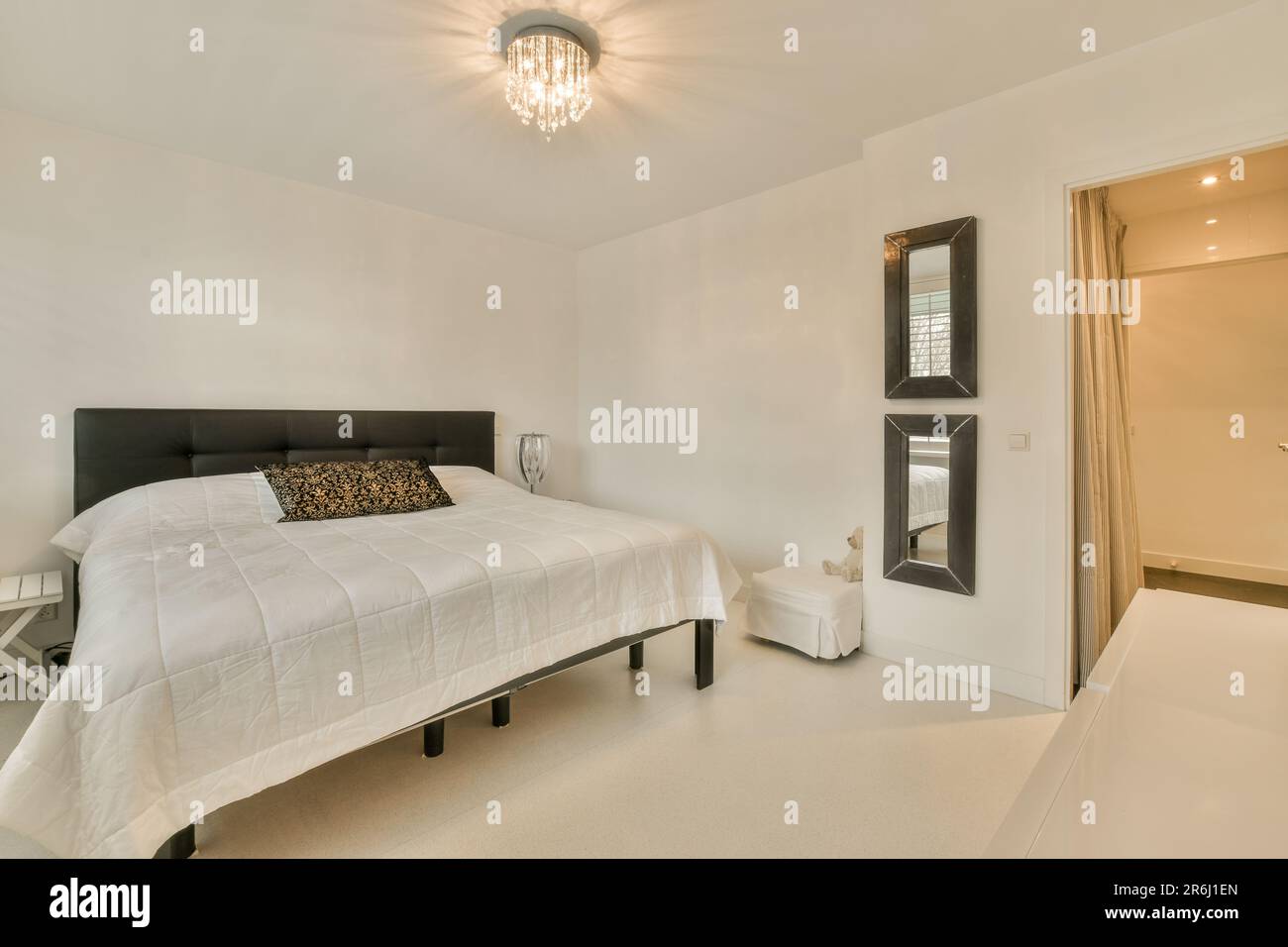 un dormitorio con una cama blanca y cabeceras negras en la pared frente a  la habitación es una puerta abierta Fotografía de stock - Alamy