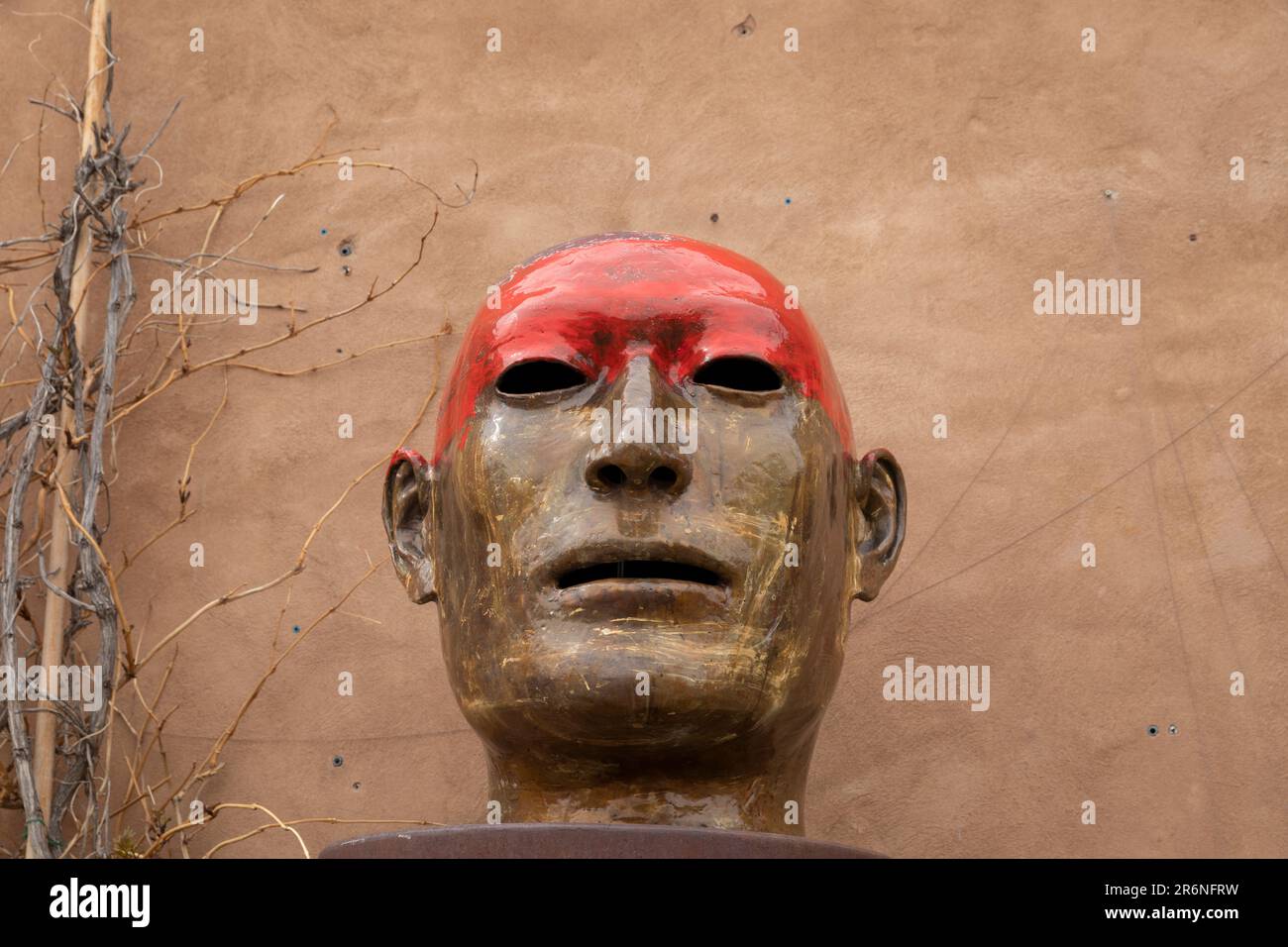Una escultura moderna de una cabeza humana domina la fachada de adobe de la galería de arte Sun & Dust a lo largo de la histórica Canyon Road en Santa Fe, Nuevo México. Foto de stock