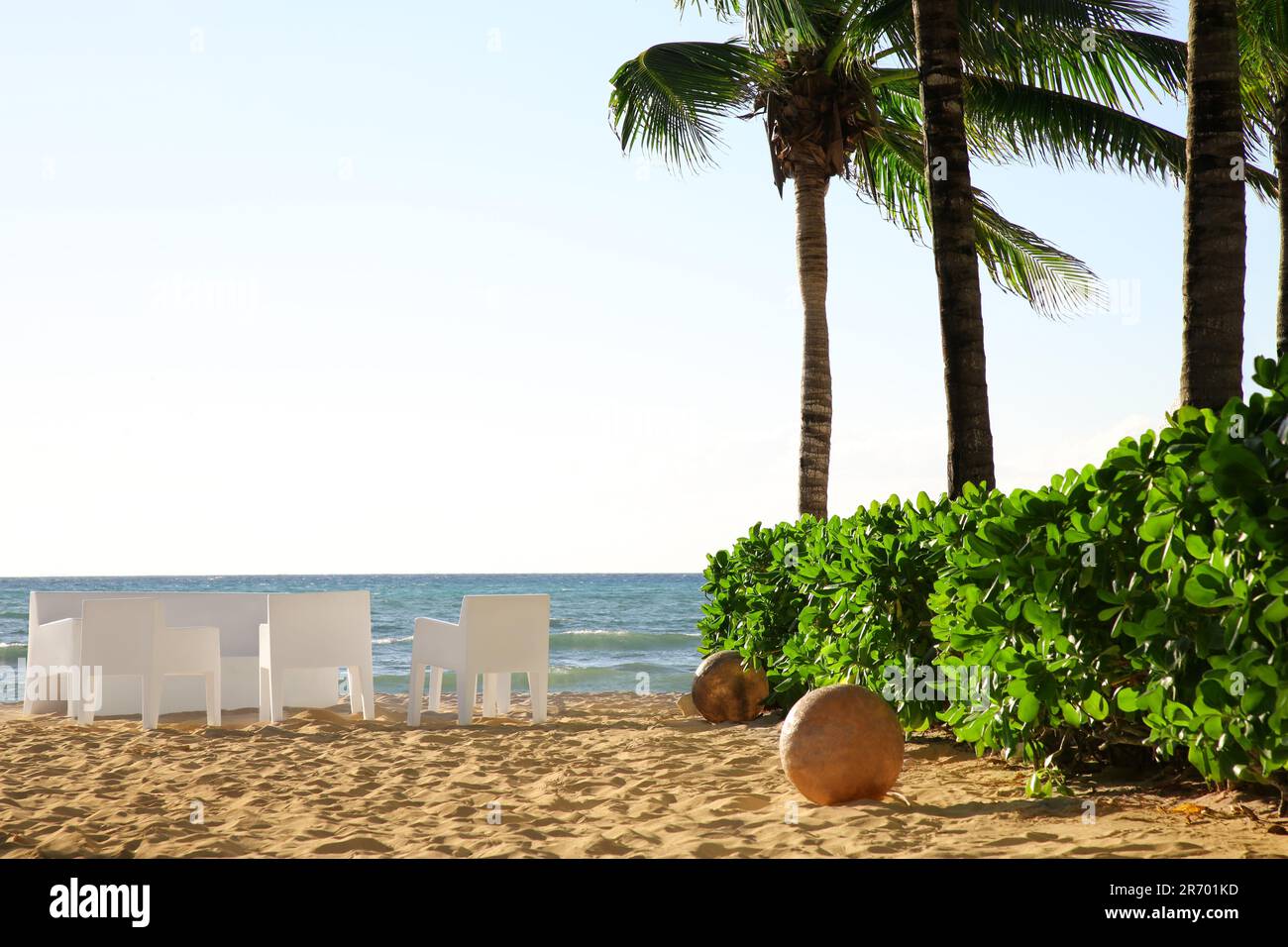 Vista pintoresca de la playa de arena, muebles y palmeras cerca del mar en el día soleado Foto de stock