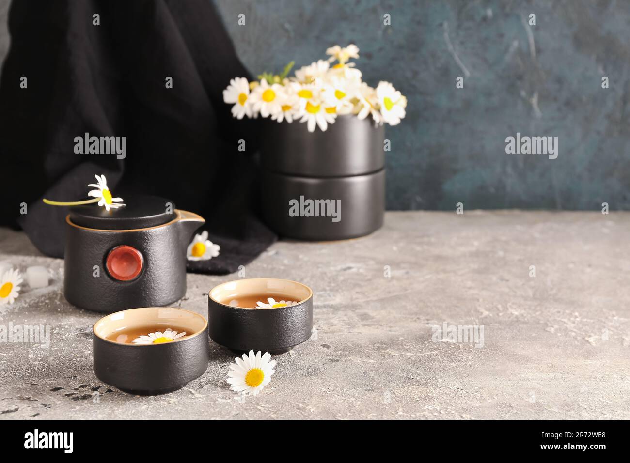 Taza de té de manzanilla natural y flores en la mesa blanca cerca de la  pared azul Fotografía de stock - Alamy