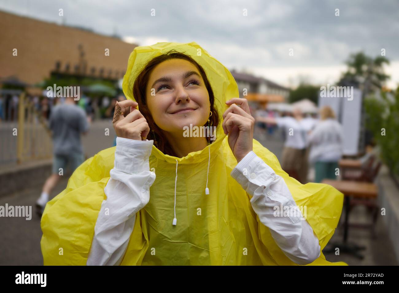 Mujer joven alegre en chubasquero en un festival de verano. Retrato de una  persona femenina disfrutando del día lluvioso en un evento público al aire  libre Fotografía de stock - Alamy