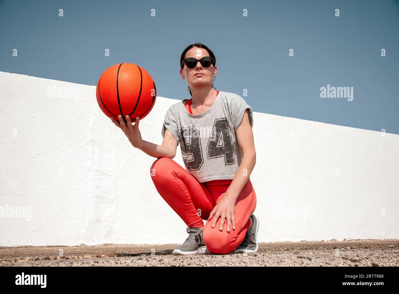 Jugador de baloncesto femenino, sosteniendo un baloncesto, fuera en el sol. Foto de stock
