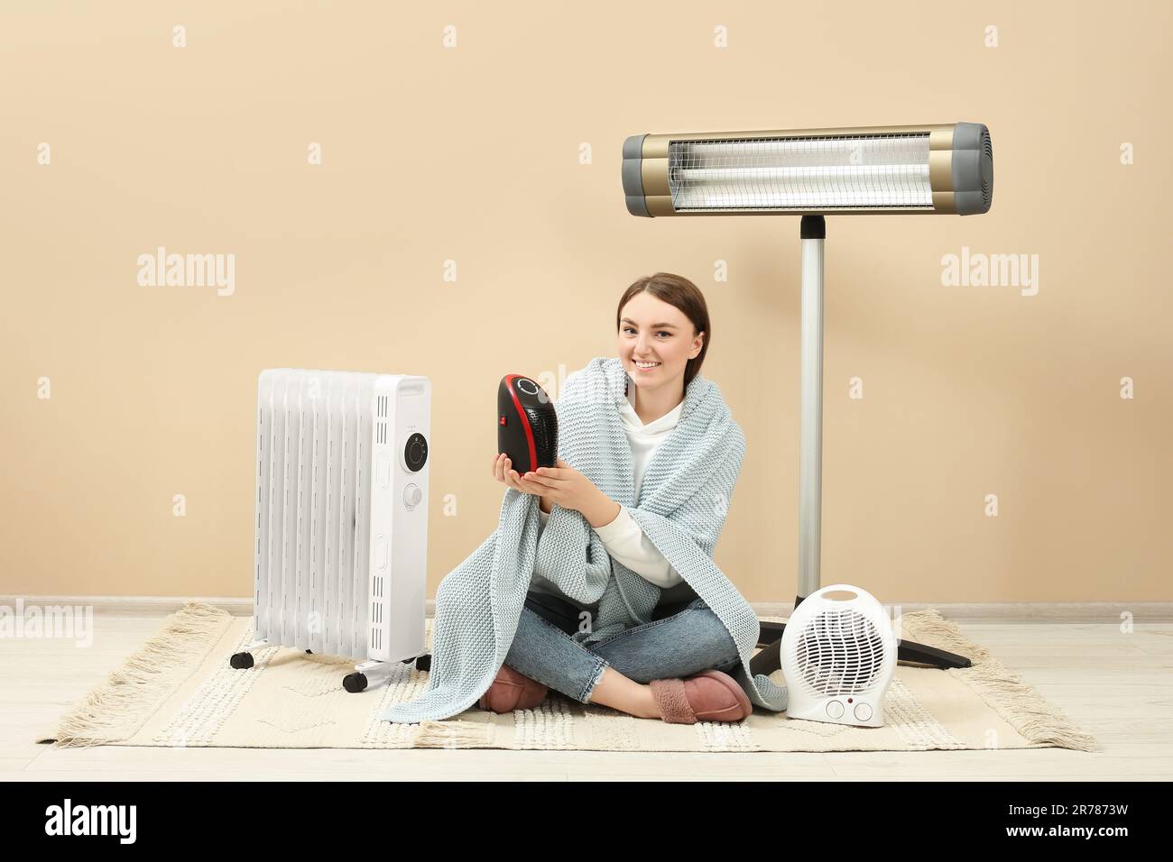 Mujer joven con diferentes calentadores eléctricos modernos cerca de la  pared beige en el interior Fotografía de stock - Alamy