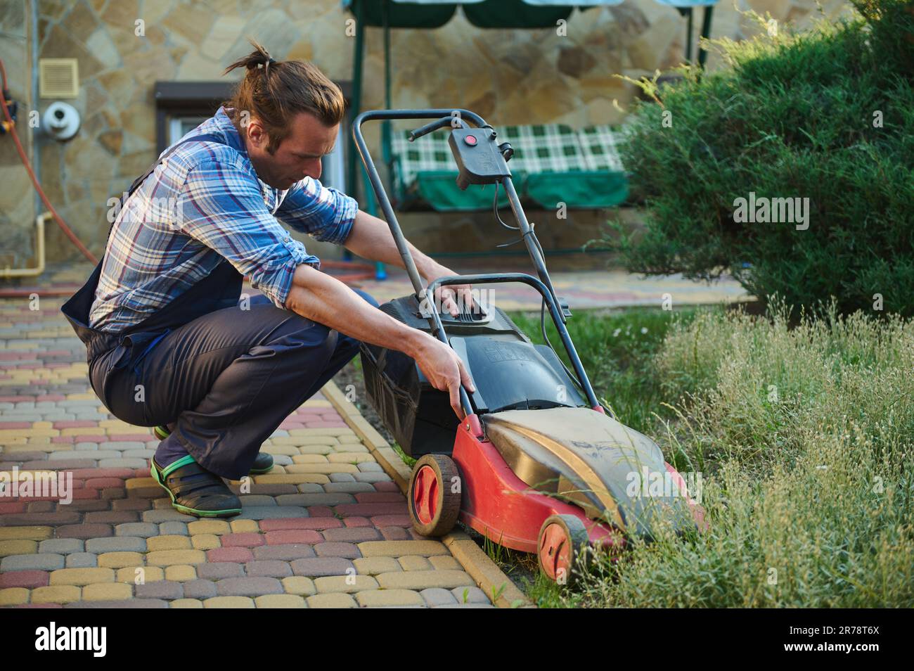 Joven jardinero paisajista colocando el filtro vacío en el cortacésped  eléctrico inalámbrico. Mantenimiento del jardín. Paisajismo Fotografía de  stock - Alamy