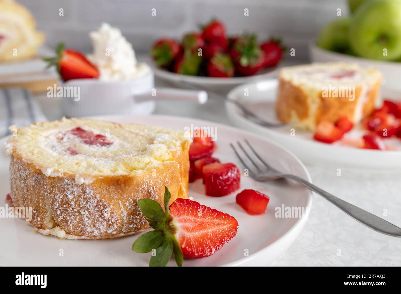 Rebanada de rollo suizo con fresas y crema Foto de stock