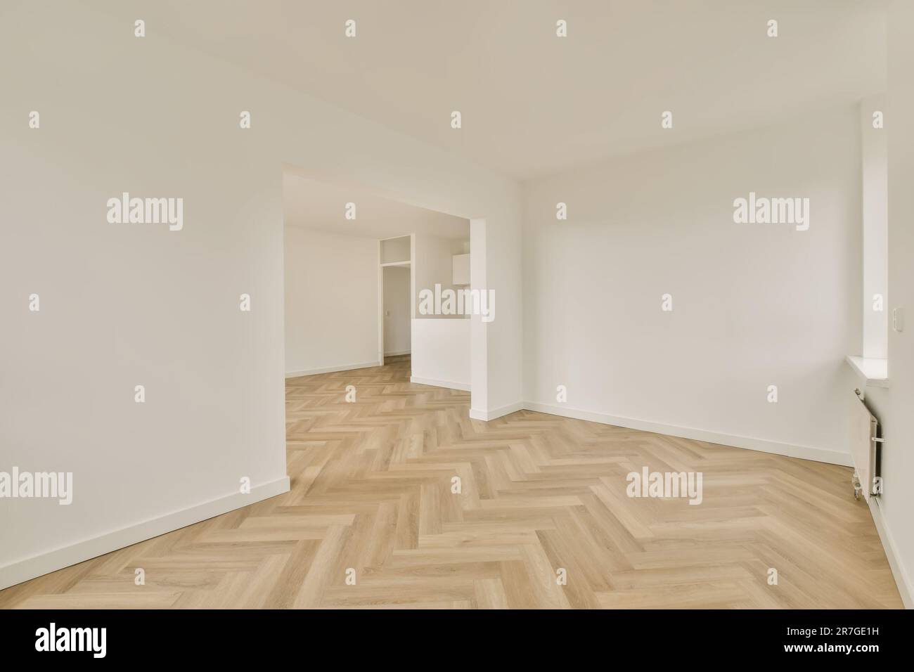 una habitación vacía con suelos de parquet y paredes blancas en las esquinas a la derecha es una puerta Foto de stock