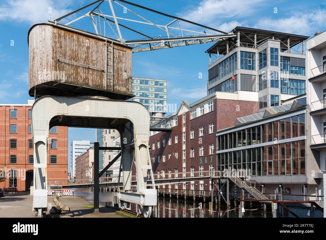 Grúa portuaria histórica en el puerto interior de Harburg. Antiguos almacenes convertidos y nuevos edificios de oficinas en el puerto. La ciudad y el distrito son Foto de stock