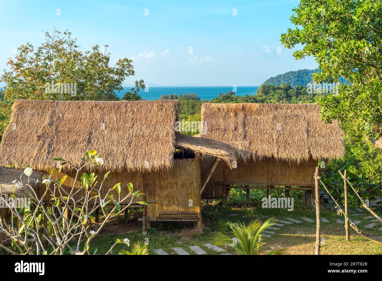 Jardín con cabañas de bambú con paja y vistas al mar en la isla de Ko Phayam en Tailandia Foto de stock