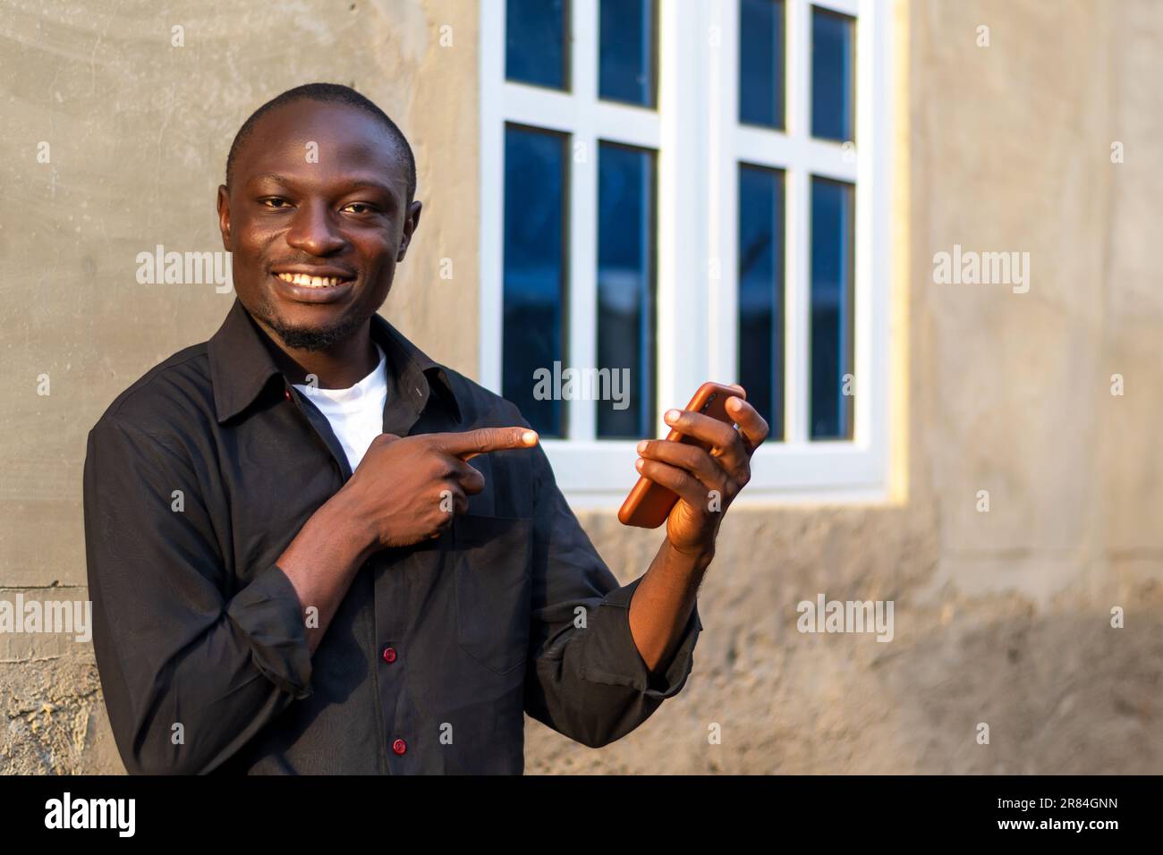 hombre negro emocionado usando su teléfono móvil. haciendo uso de la tecnología inalámbrica Foto de stock