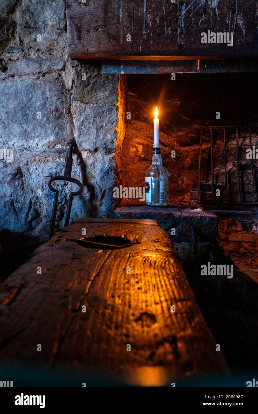 Una vela en una botella en una vieja casa de piedra Foto de stock