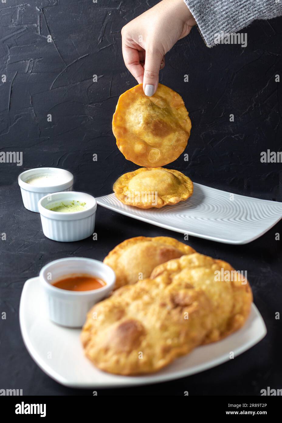 Pastelito Comida tradicional venezolana en backgroud oscuro, tres salsa Foto de stock