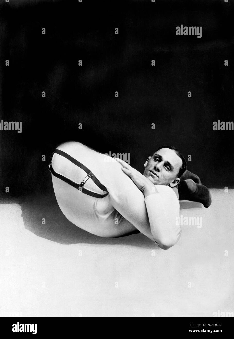 Buffalo, Nueva York: c. 1920. Un contorsionista pone sus piernas detrás de su espalda en un anuncio para la compañía del tío Sam Truss Foto de stock