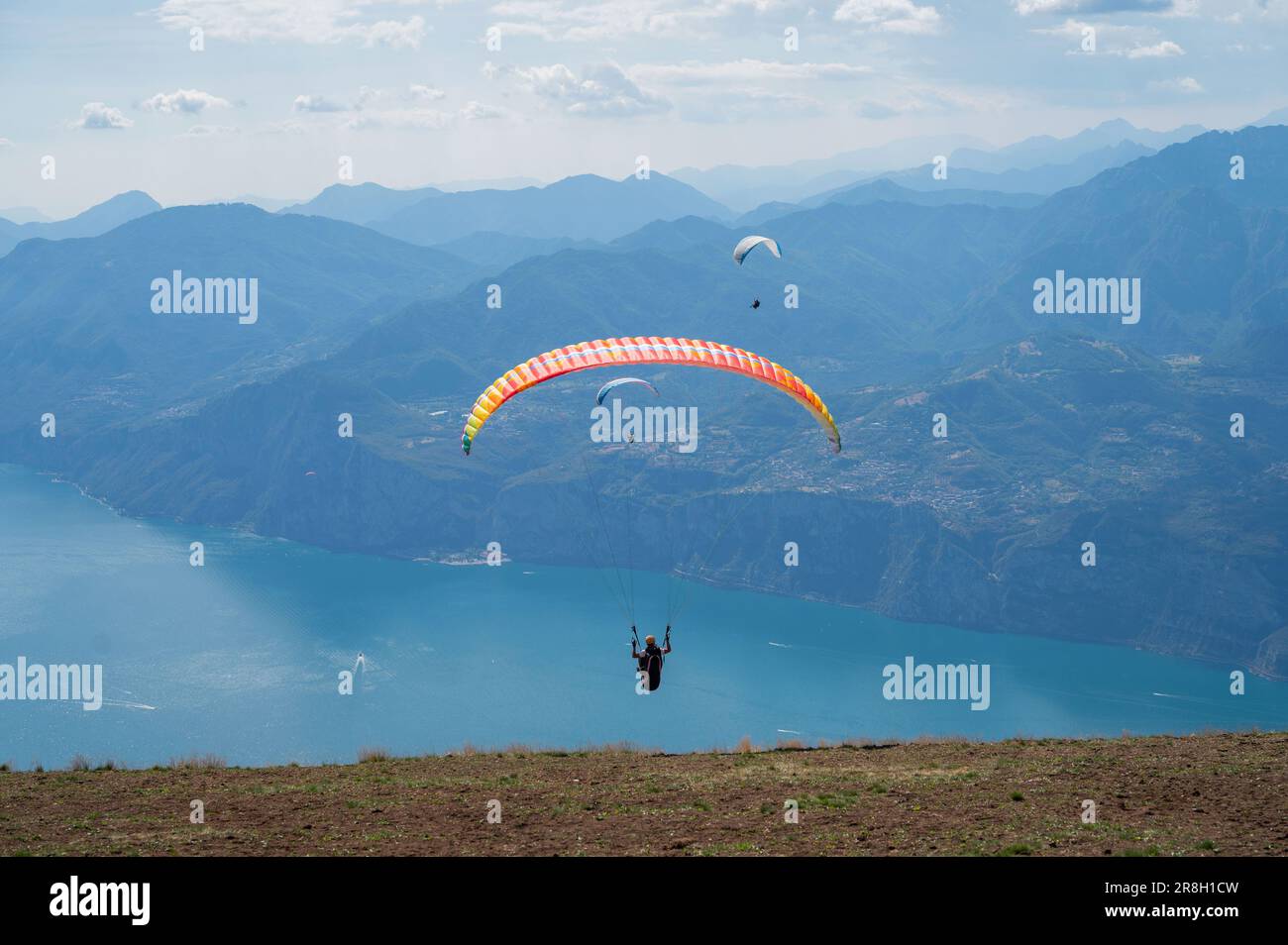 Los parapentes saltan desde la cima del Monte Baldo, hacia Maclesine y el lago de Garda en Italia Foto de stock