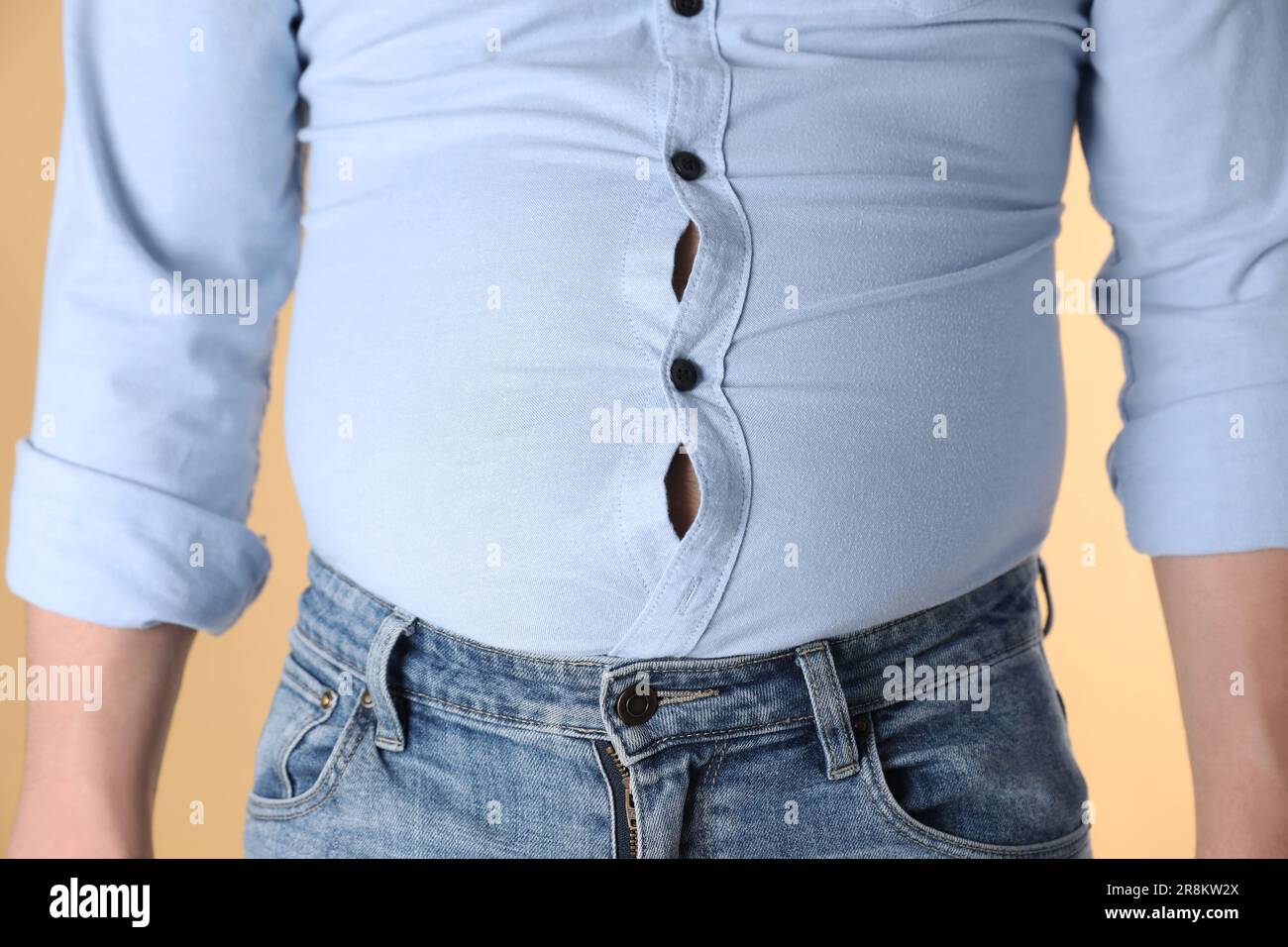 Hombre con sobrepeso en camisa apretada sobre fondo amarillo