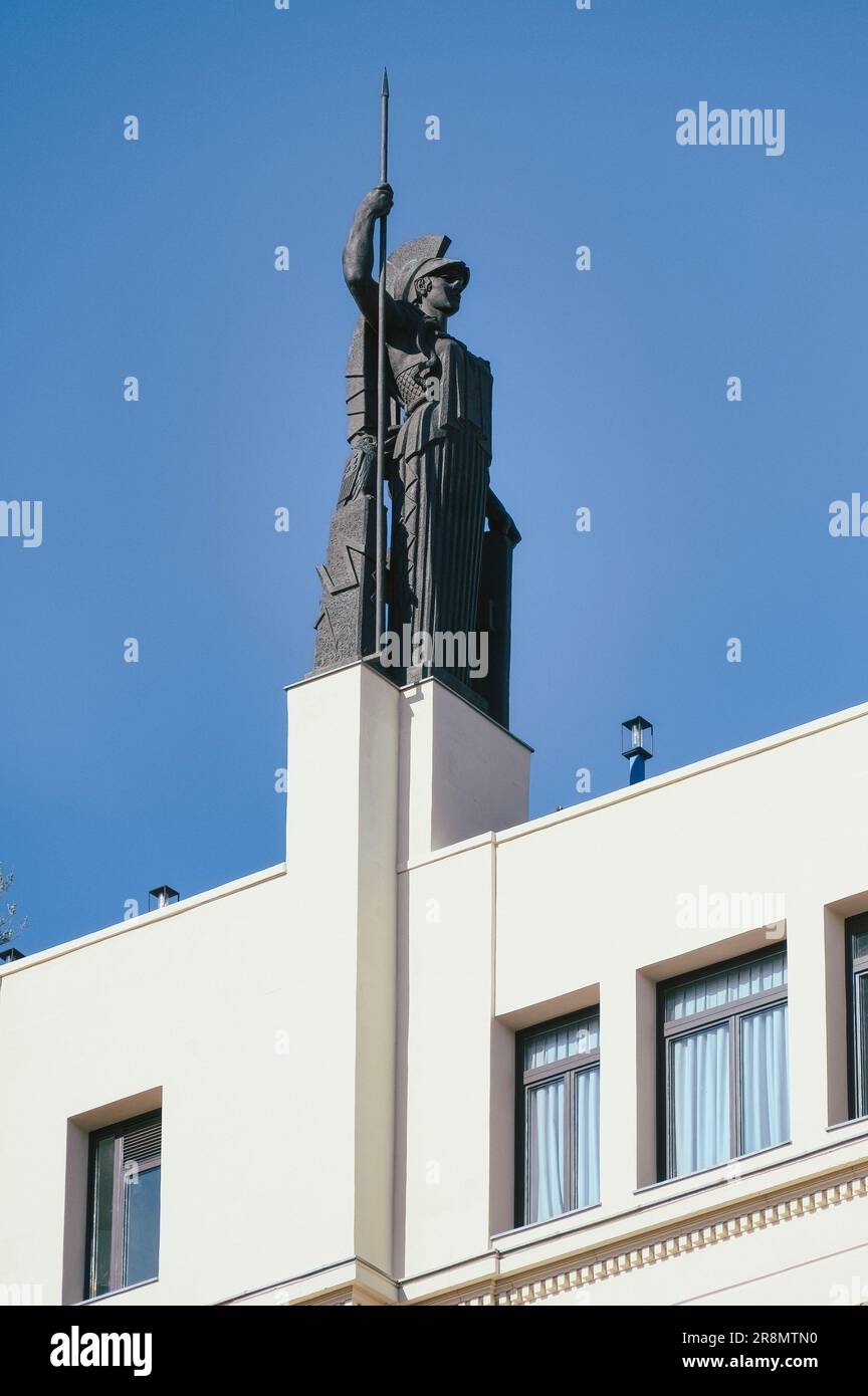 Madrid, ESPAÑA - 19 de julio de 2022: Estatua de un hombre que lleva un casco morión español y sostiene una varilla larga en la parte superior de un edificio blanco. El material gráfico sirve a. Foto de stock