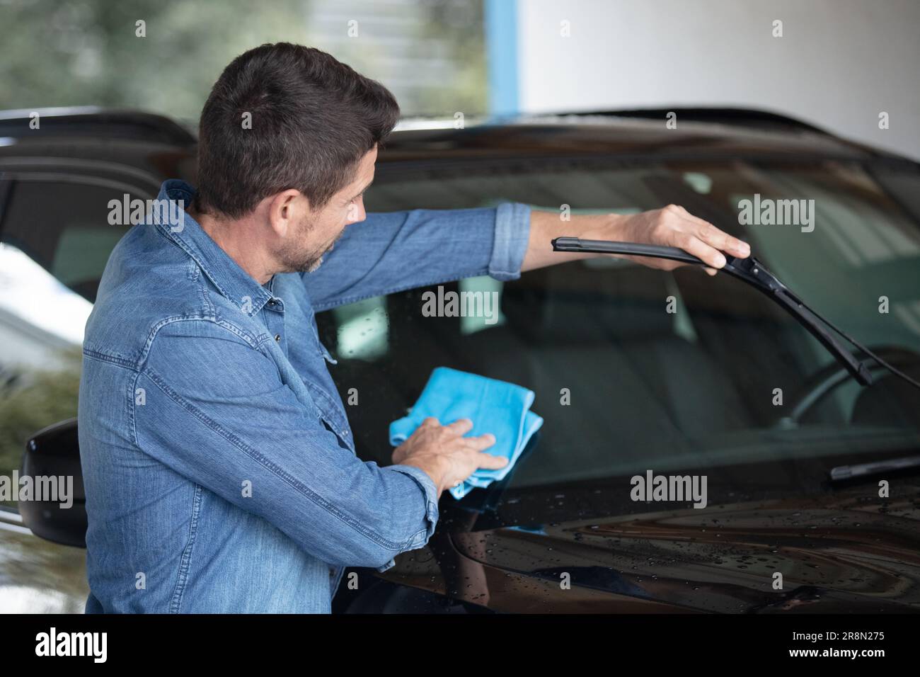 hombre en uniforme y respirador, trabajador del centro de lavado de autos,  limpieza del cepillo de limpieza interior del auto. concepto de detalle de  coche. 8661439 Foto de stock en Vecteezy